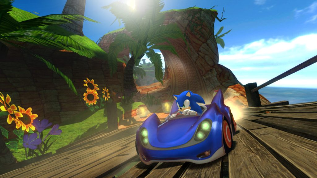 A screenshot from Sonic & All-Stars Racing, released in 2010. Sonic drives a blue car across a wooden bridge, leaving behind a rocky landscape.