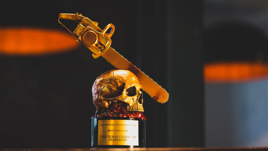 The Fangoria Awards trophy for The Texas Chain Saw Massacre as 'Best Game'. The trophy is all gold and features a skull on a plaque, with a chain saw mid way through it.