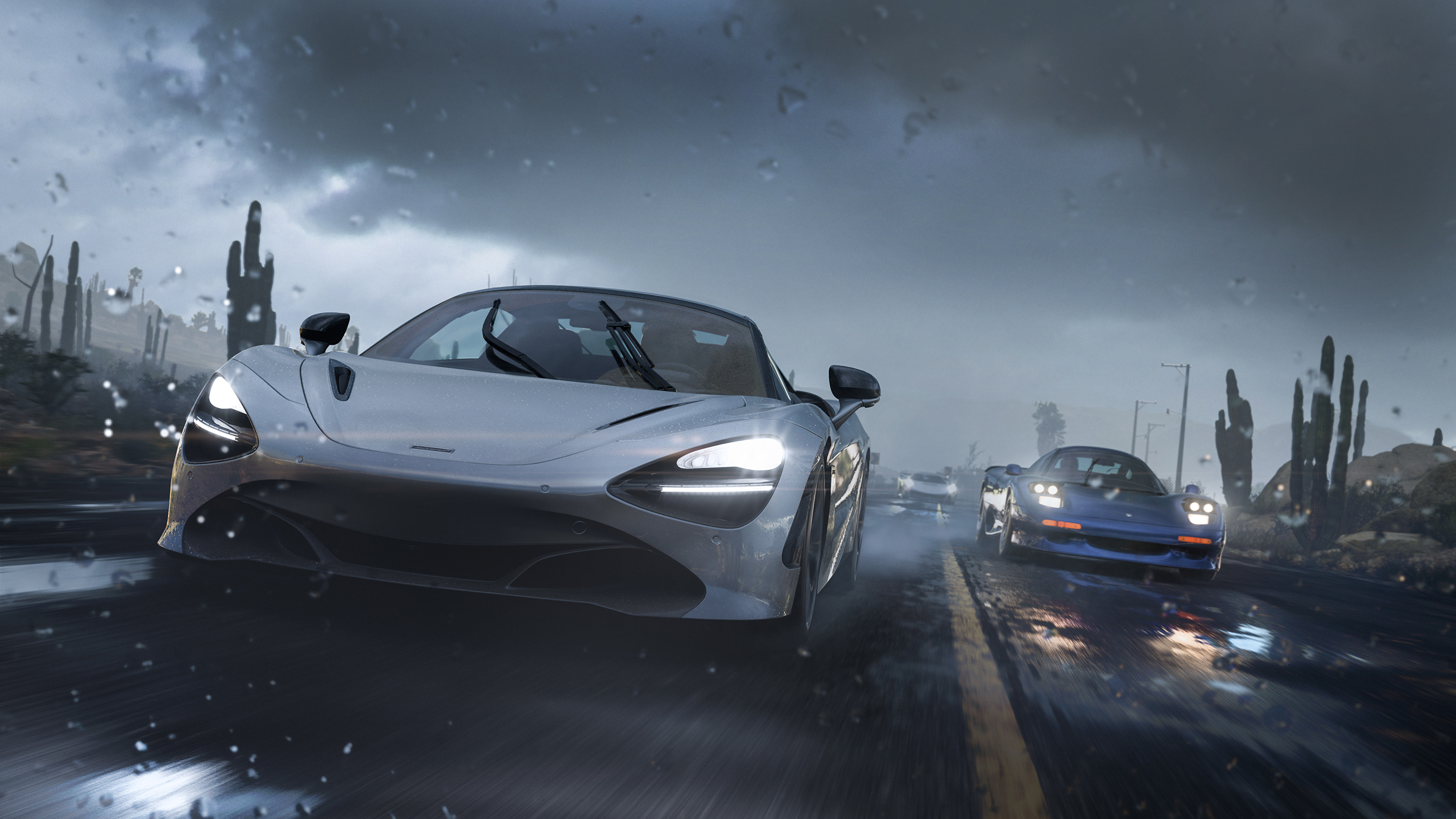 A silver sports car speeds down a wet, dark road in rainy weather, with another blue car following behind. Rain droplets and motion blur emphasise the high-speed, intense driving scene. Cacti line the roadside.
