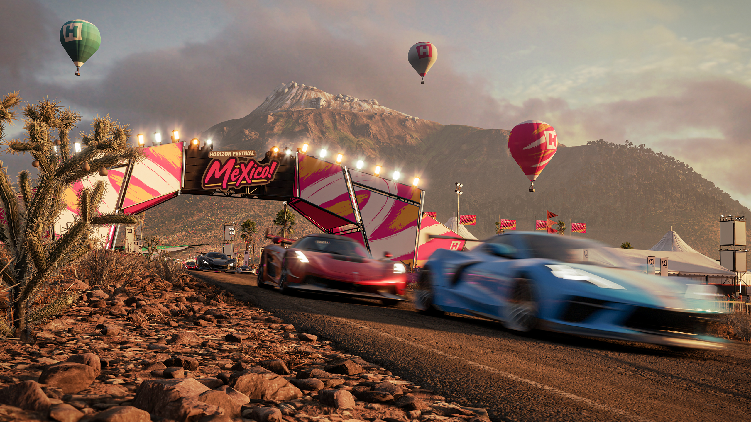 A vibrant car race with motion-blurred sports cars speeding past a Horizon Festival Mexico sign, set against a mountainous landscape, hot air balloons, cacti, and festival tents at sunset.